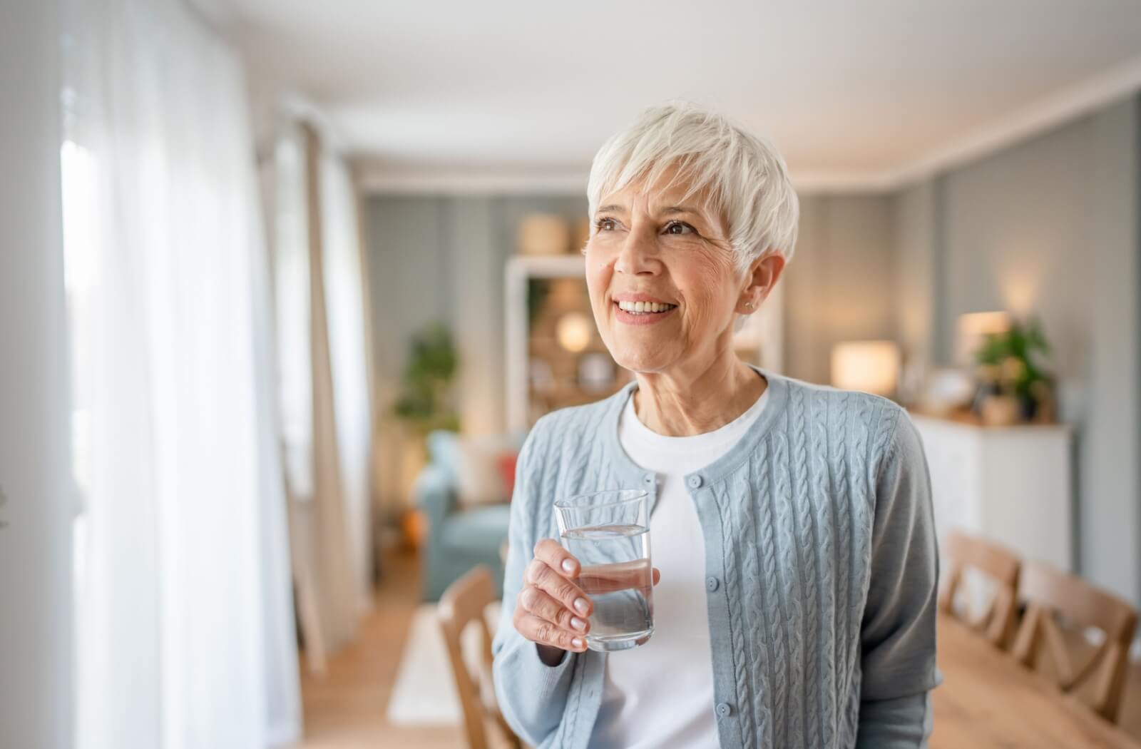 A senior sips a drink in their independent living apartment.